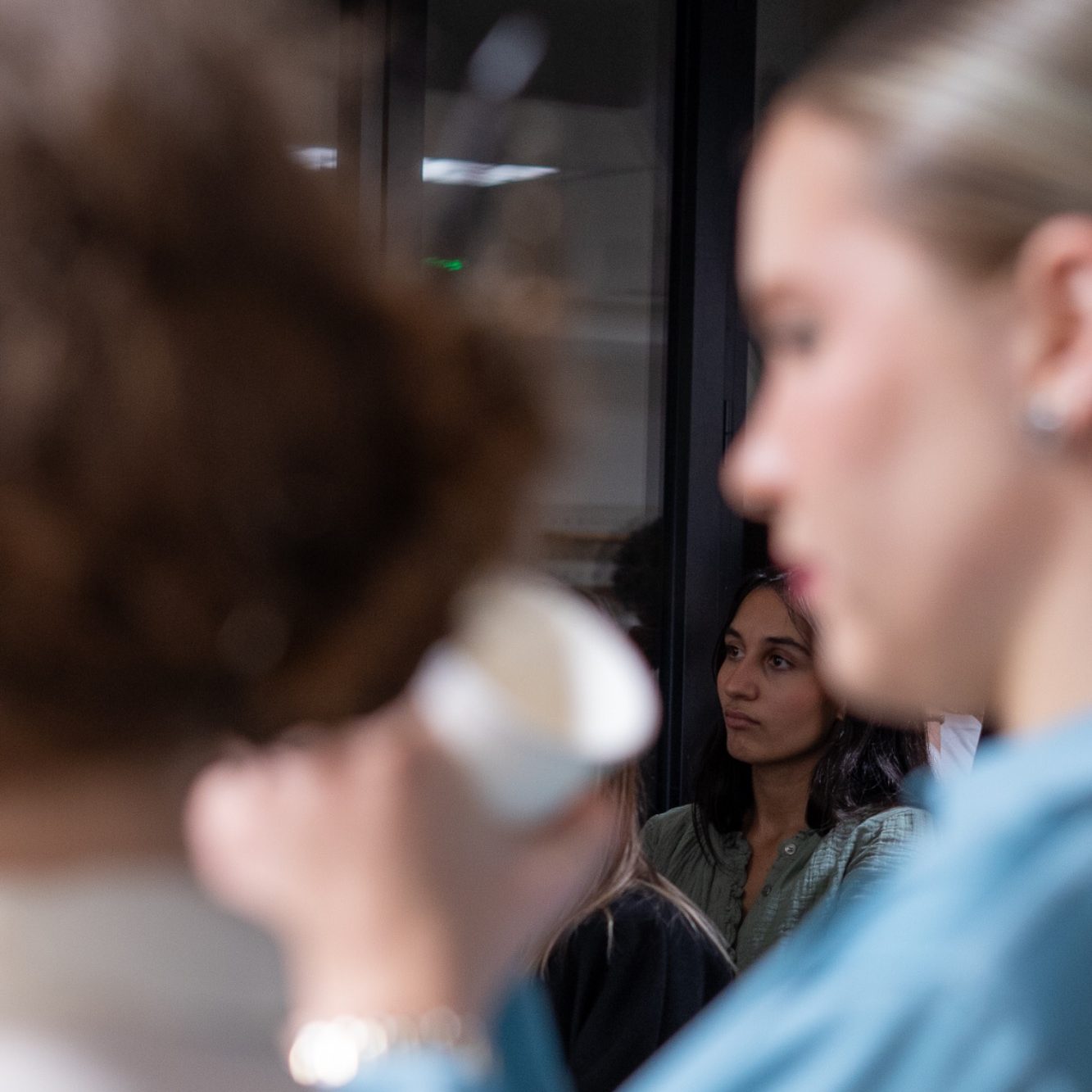 Deux femmes en arrière-plan, l'une tenant une tasse, l'autre regardant fixement.