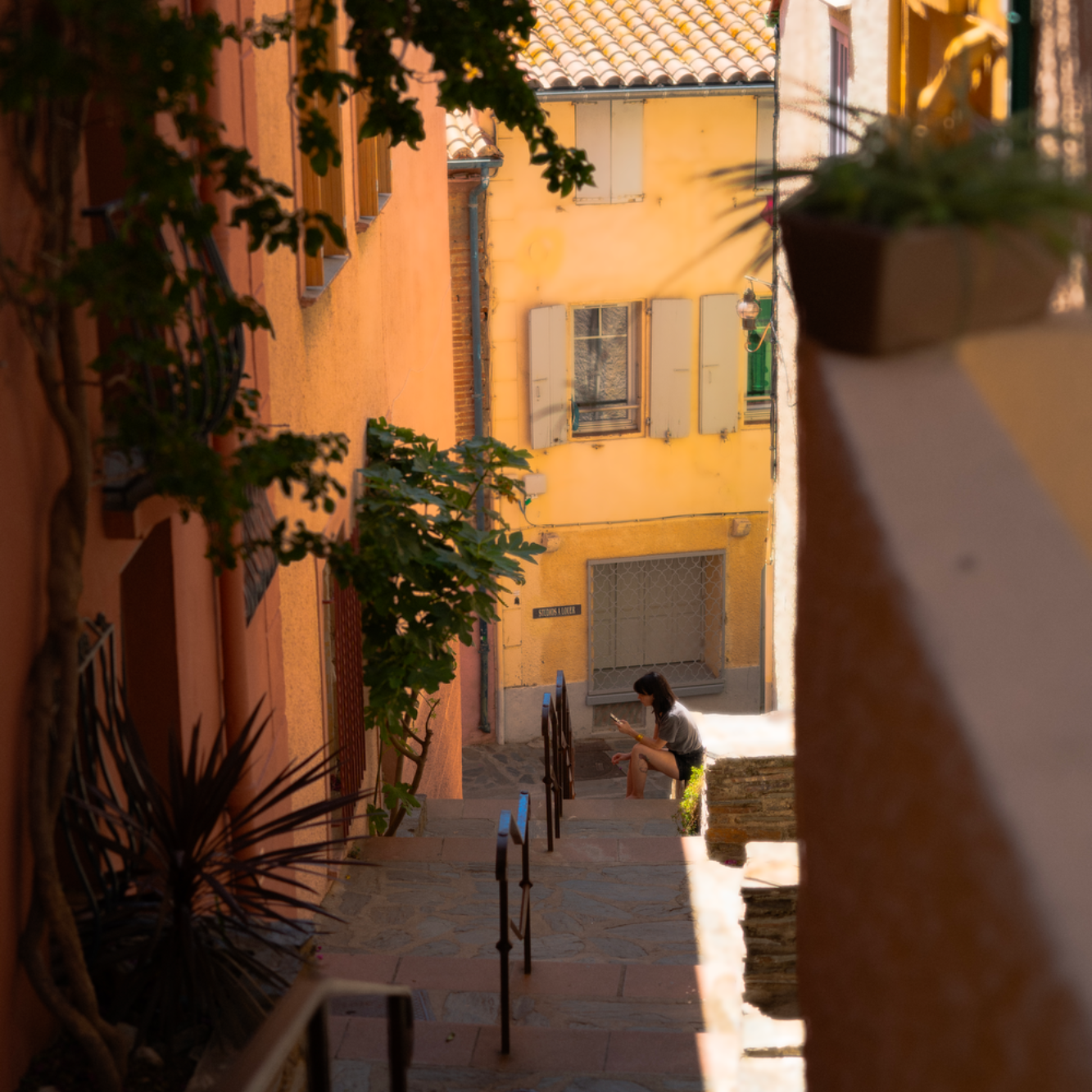 Ruelle étroite avec murs colorés et une personne assise sur un banc.